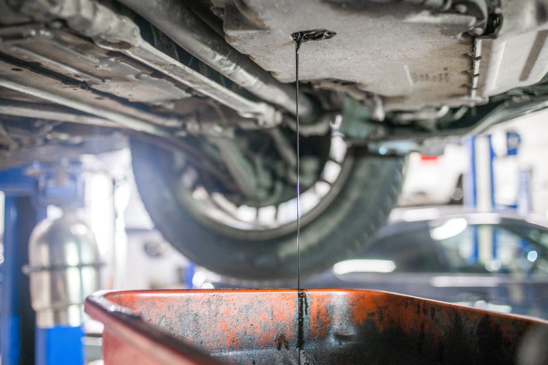 Undercarriage of a vehicle in a service bay with fluid draining into a pan