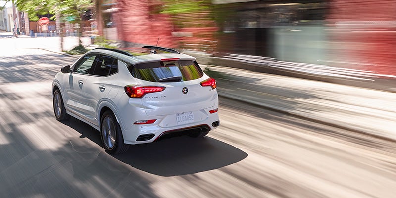 Rear view of a white Buick Encore GX driving down a city street