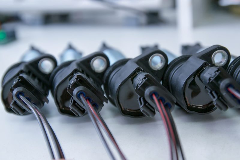 Close-up of multiple ignition coils lined up on a white surface.