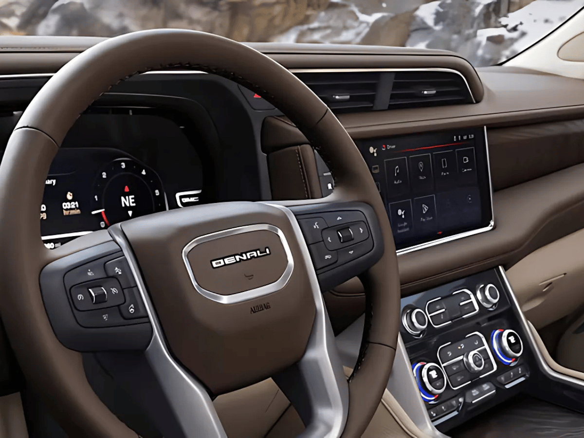 Close-up of the 2025 GMC Denali interior showcasing the leather-wrapped steering wheel, digital driver display, and infotainment system